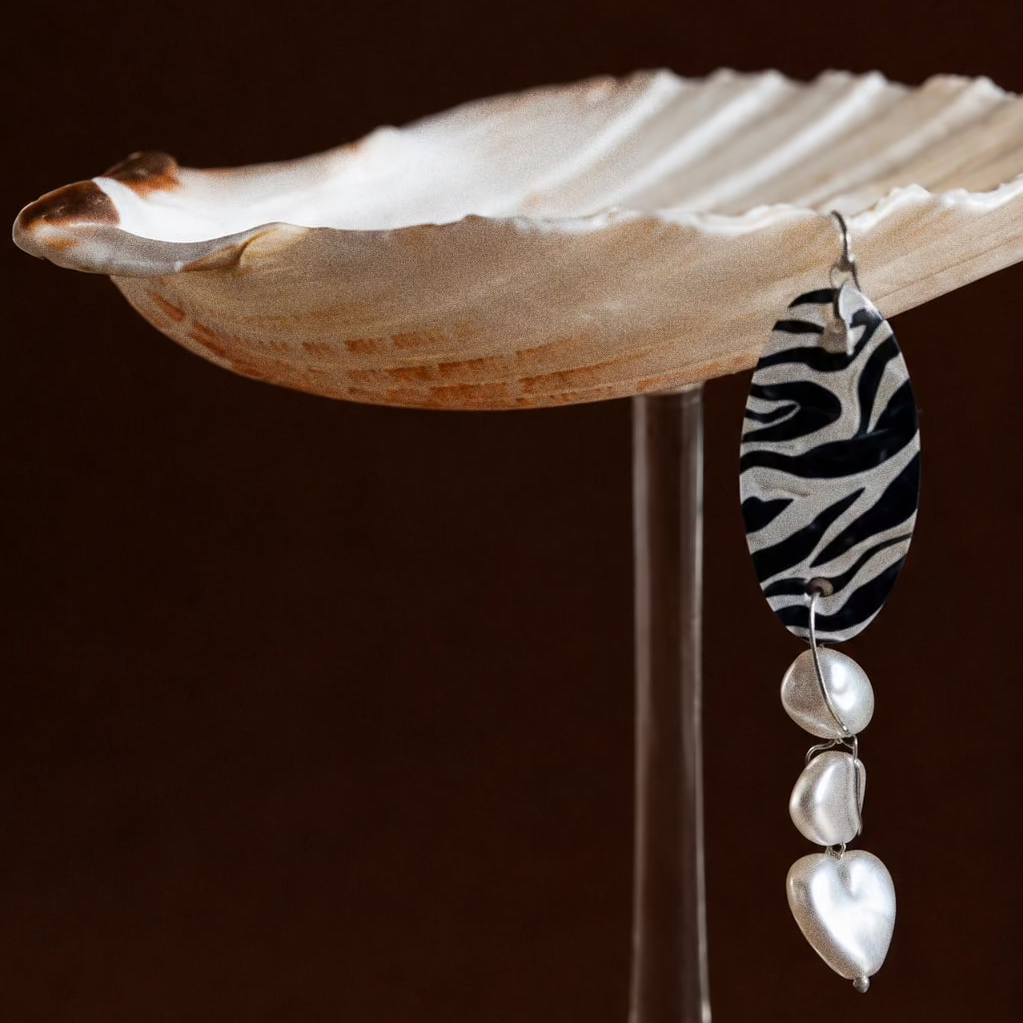 Close-up of scallop shell coupe with zebra print capiz charm and pearl beads